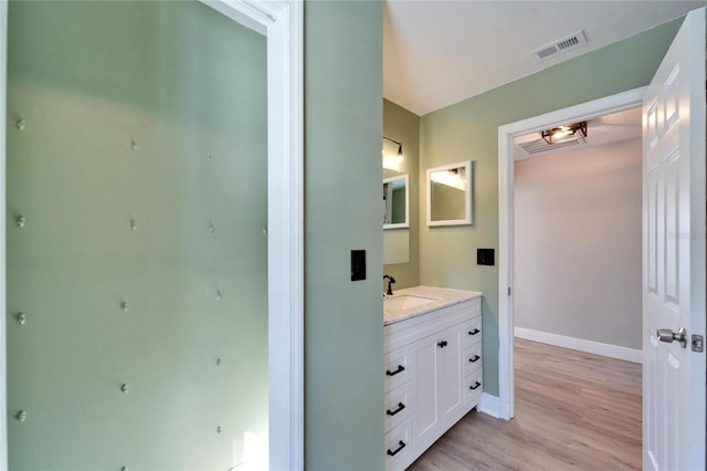 bathroom with visible vents, vanity, baseboards, and wood finished floors