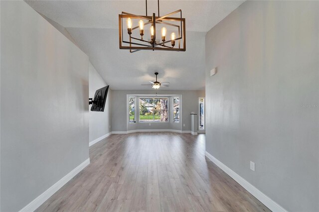 unfurnished living room featuring baseboards, a textured ceiling, a ceiling fan, and light wood-style floors