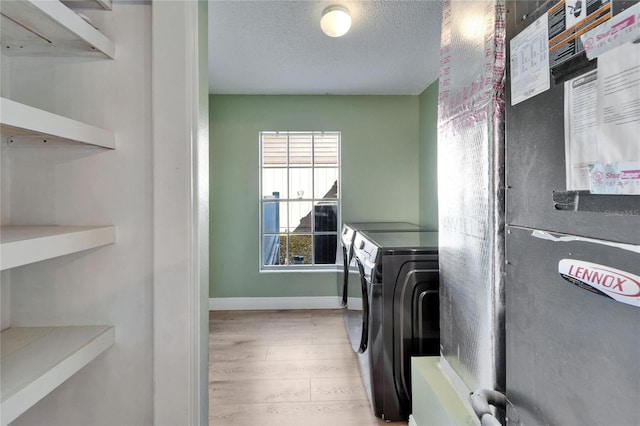 laundry area featuring light wood-style floors, a textured ceiling, separate washer and dryer, laundry area, and baseboards