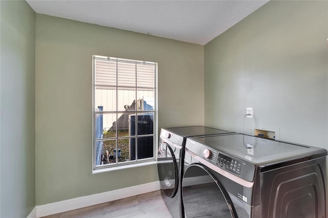 laundry room with a textured ceiling, laundry area, baseboards, light wood finished floors, and washer and clothes dryer