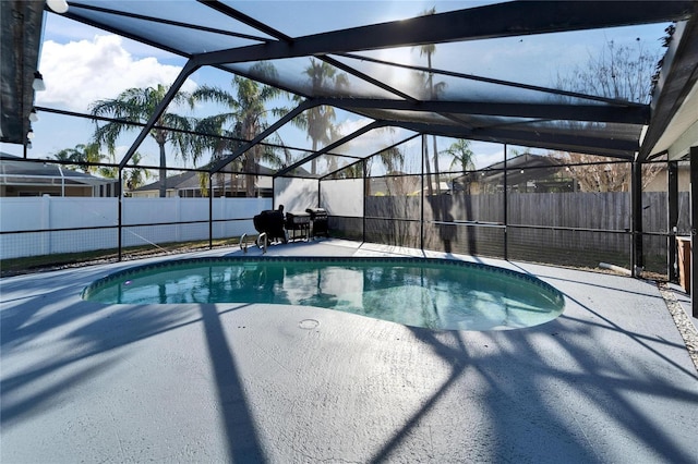 view of pool featuring glass enclosure, a patio, a fenced backyard, and a fenced in pool