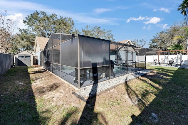 back of property featuring a patio, a fenced backyard, a lanai, a storage shed, and a fenced in pool