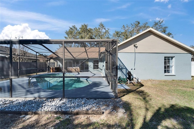 back of property with a fenced in pool, a lawn, a lanai, fence, and stucco siding