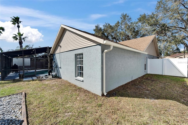 view of home's exterior with a fenced in pool, a lanai, fence, a yard, and stucco siding