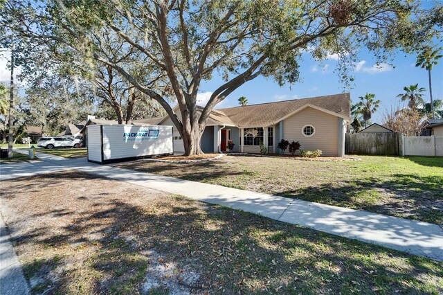 ranch-style home featuring fence and a front lawn