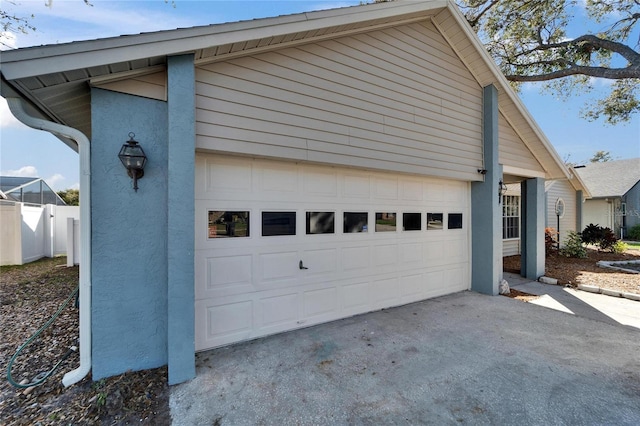 garage featuring driveway and fence