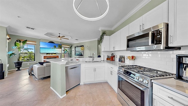 kitchen featuring appliances with stainless steel finishes, open floor plan, light countertops, and a peninsula