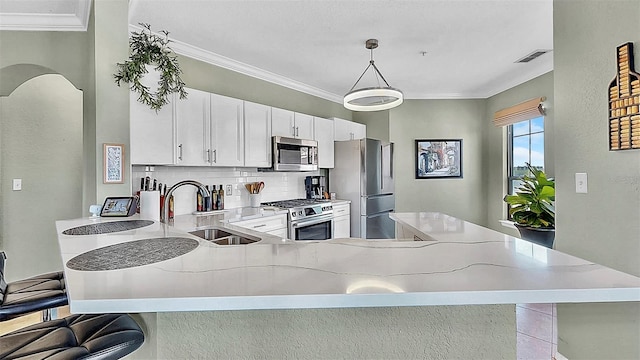 kitchen with decorative light fixtures, backsplash, appliances with stainless steel finishes, white cabinetry, and a sink