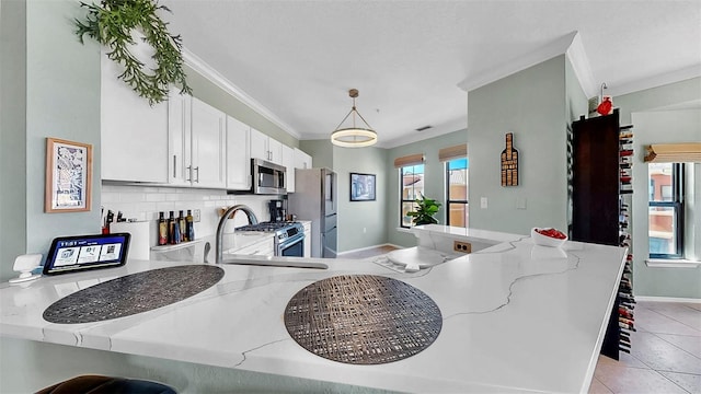 kitchen with a peninsula, stainless steel appliances, crown molding, and decorative light fixtures