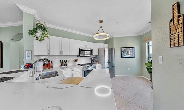 kitchen featuring appliances with stainless steel finishes, white cabinets, a sink, and decorative light fixtures