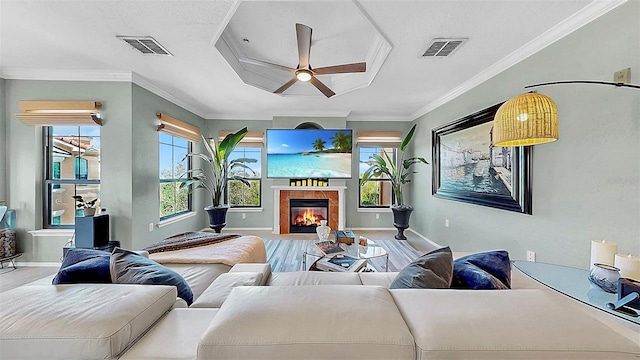 living area featuring a wealth of natural light, visible vents, and crown molding