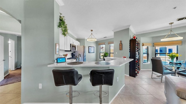 kitchen featuring white cabinets, appliances with stainless steel finishes, a breakfast bar area, a peninsula, and light countertops