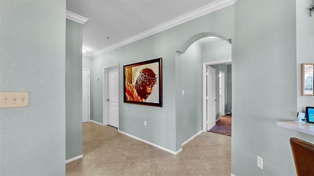 hallway with light tile patterned floors, baseboards, arched walkways, and crown molding