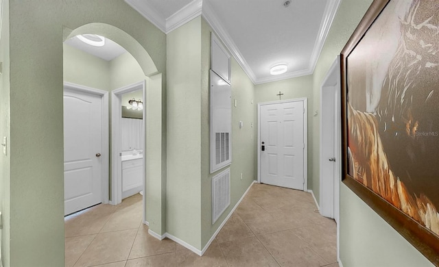 corridor with ornamental molding, arched walkways, baseboards, and light tile patterned floors