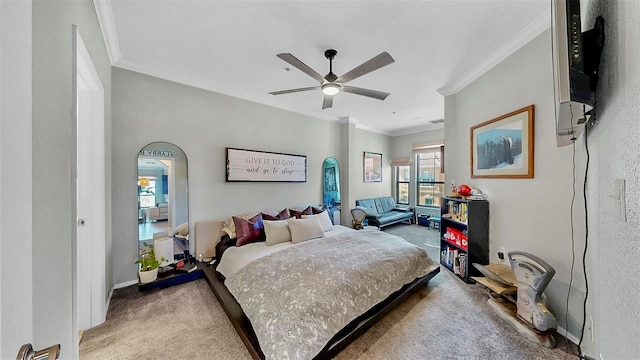 carpeted bedroom featuring a ceiling fan, arched walkways, crown molding, and baseboards