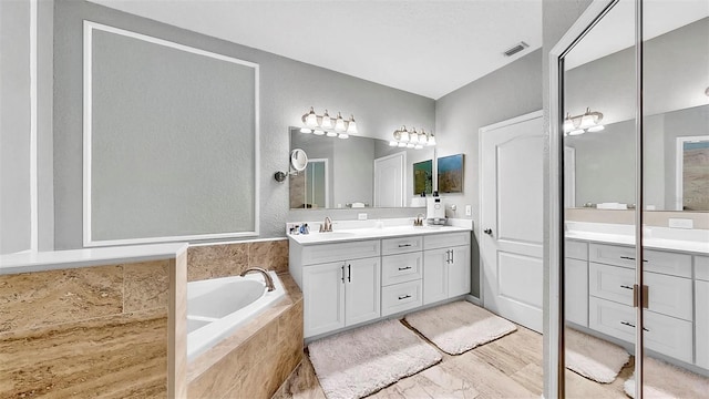 full bath with a garden tub, double vanity, a sink, and visible vents