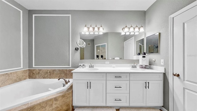 bathroom featuring a textured wall, double vanity, a sink, and a bath