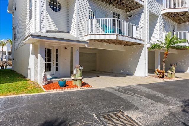 entrance to property featuring a garage, driveway, french doors, and stucco siding