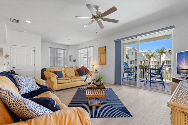 living room featuring light wood-style floors, baseboards, visible vents, and a ceiling fan