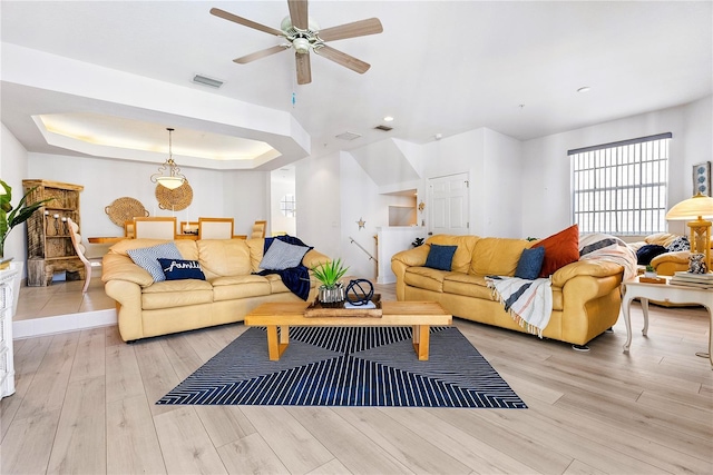 living room featuring wood finished floors, a raised ceiling, and visible vents