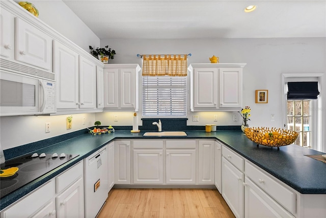 kitchen featuring white appliances, dark countertops, and a sink