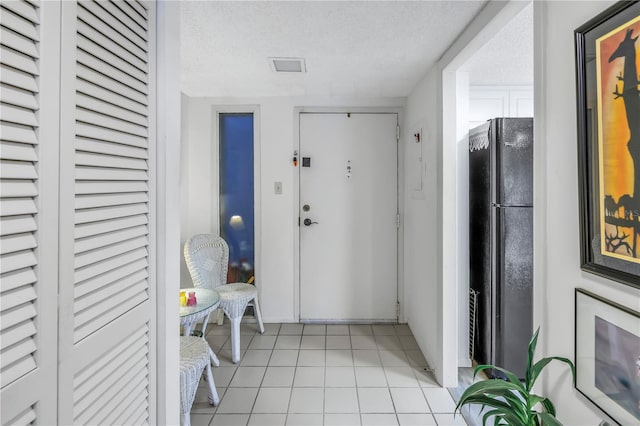 hallway featuring light tile patterned floors and a textured ceiling