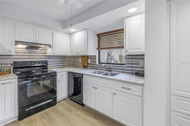 kitchen with light wood finished floors, white cabinets, under cabinet range hood, black appliances, and a sink