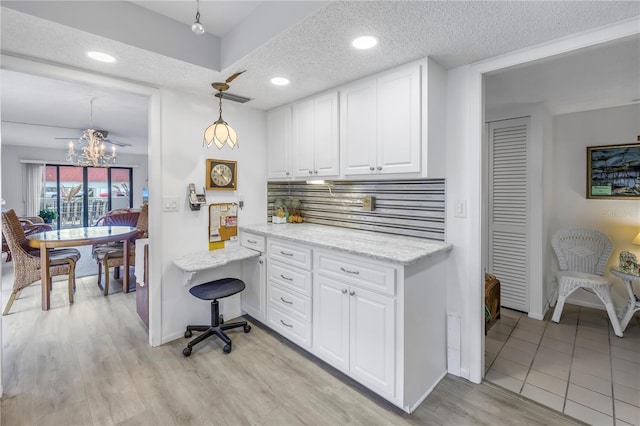 kitchen featuring light wood-style flooring, white cabinets, a textured ceiling, and decorative backsplash