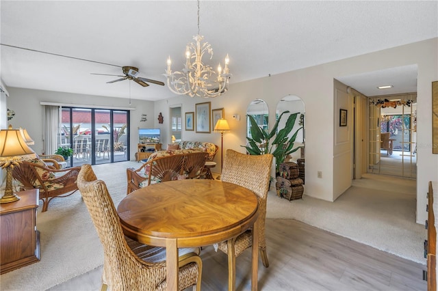 dining space with light colored carpet, a textured ceiling, and ceiling fan with notable chandelier