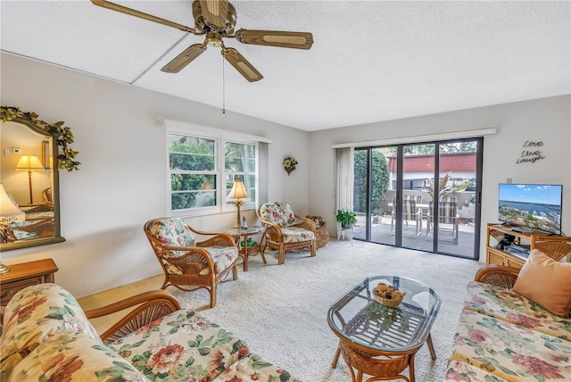 carpeted living area with ceiling fan and a textured ceiling