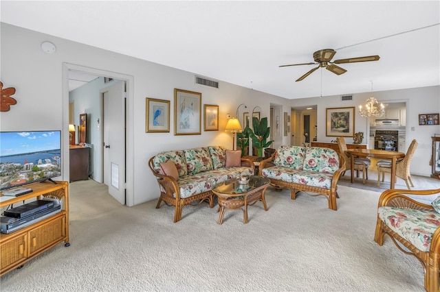 living room featuring ceiling fan with notable chandelier, visible vents, and light colored carpet