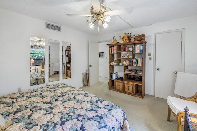 bedroom featuring light carpet, ceiling fan, visible vents, and a textured ceiling