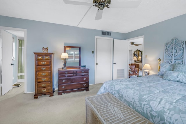 carpeted bedroom featuring ensuite bath, visible vents, and a ceiling fan