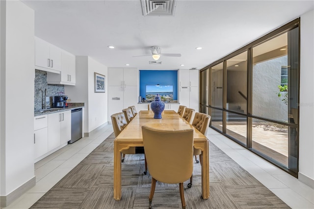 dining space with baseboards, visible vents, a ceiling fan, a wall of windows, and light tile patterned flooring