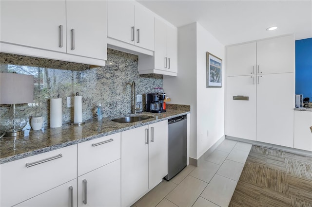 kitchen with a sink, decorative backsplash, dark stone counters, and stainless steel dishwasher