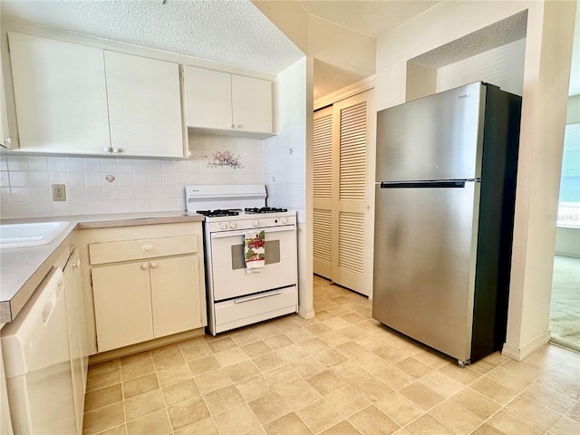 kitchen featuring a textured ceiling, white appliances, white cabinets, light countertops, and decorative backsplash