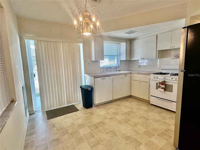 kitchen with white appliances, light countertops, white cabinetry, pendant lighting, and a sink