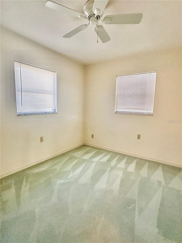 spare room with light carpet, ceiling fan, and baseboards