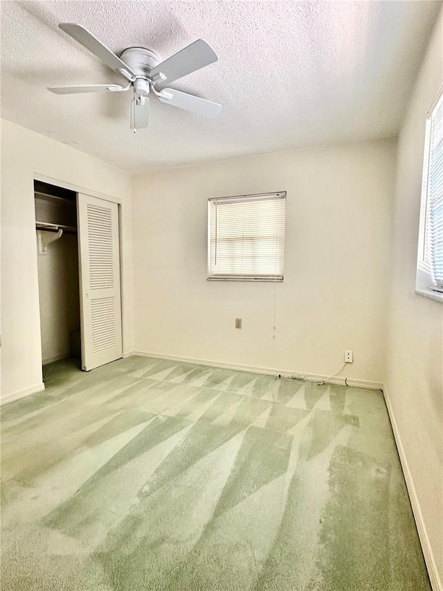 unfurnished bedroom with a textured ceiling, ceiling fan, a closet, and carpet flooring