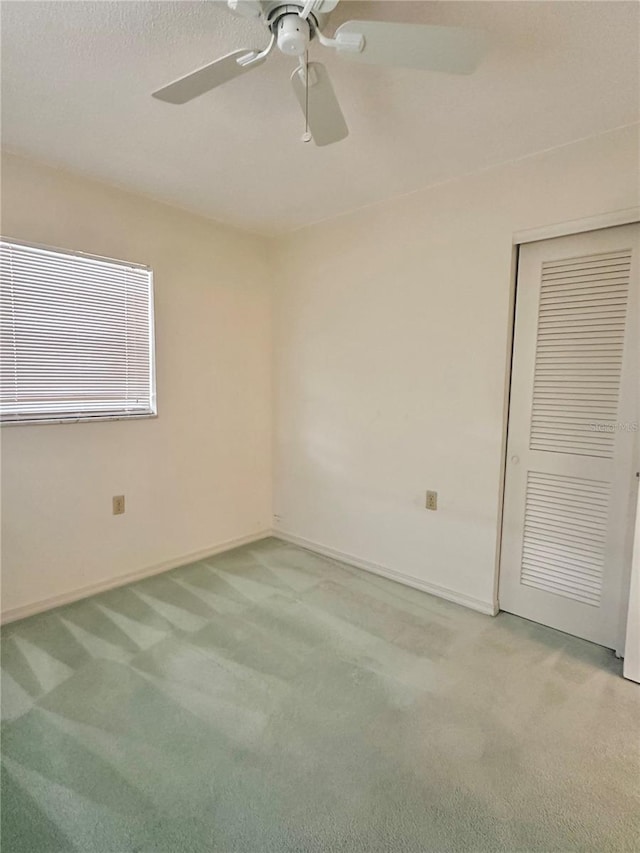 unfurnished bedroom featuring carpet, ceiling fan, and a closet