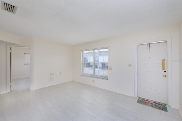 unfurnished living room with light wood finished floors and visible vents