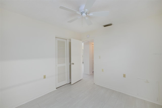 empty room featuring visible vents, a ceiling fan, and baseboards