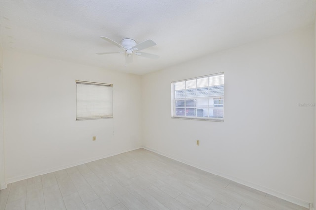 spare room with baseboards, ceiling fan, and light wood-style flooring