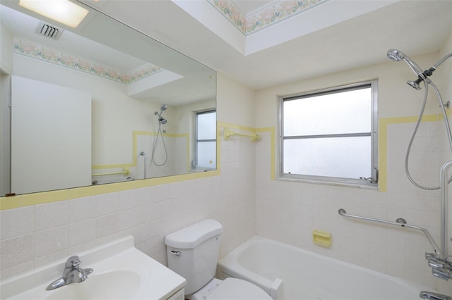 bathroom with vanity, toilet, tile walls,  shower combination, and visible vents