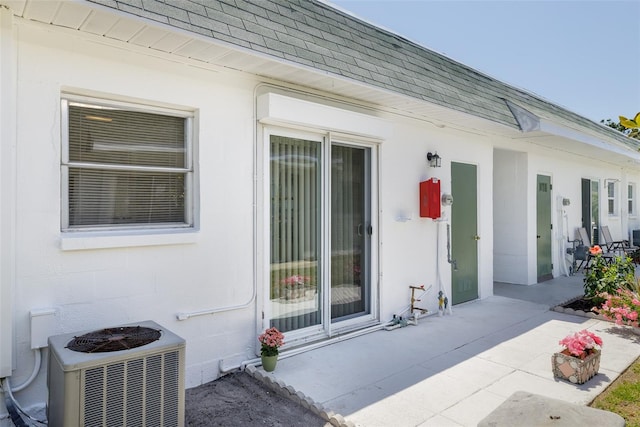 property entrance with roof with shingles and cooling unit