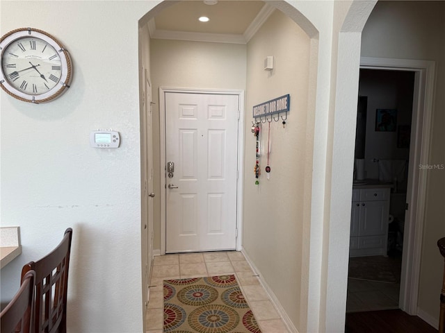 foyer entrance featuring arched walkways, light tile patterned floors, recessed lighting, ornamental molding, and baseboards