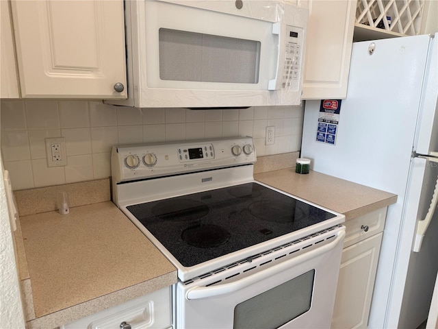 kitchen with white appliances, white cabinetry, light countertops, and decorative backsplash