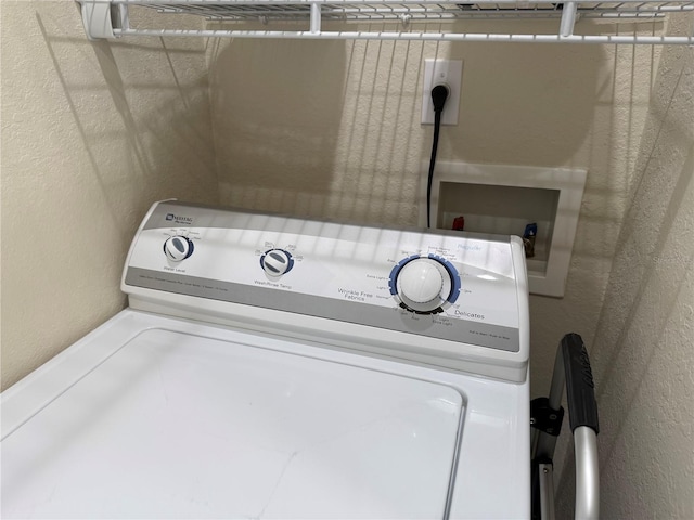 laundry room with a textured wall, laundry area, and washer / dryer