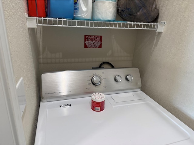 washroom featuring a textured wall, washer / clothes dryer, and laundry area