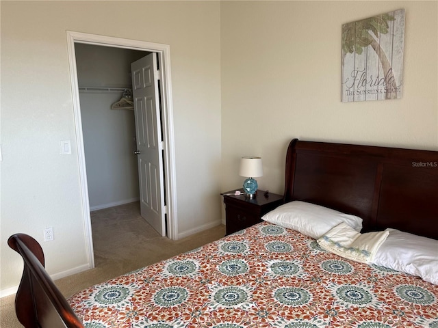 carpeted bedroom with a spacious closet, baseboards, and a closet